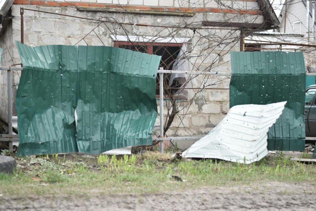 Old house with a damaged and rusted metal fence. Signs of neglect and decay in an outdoor setting.
